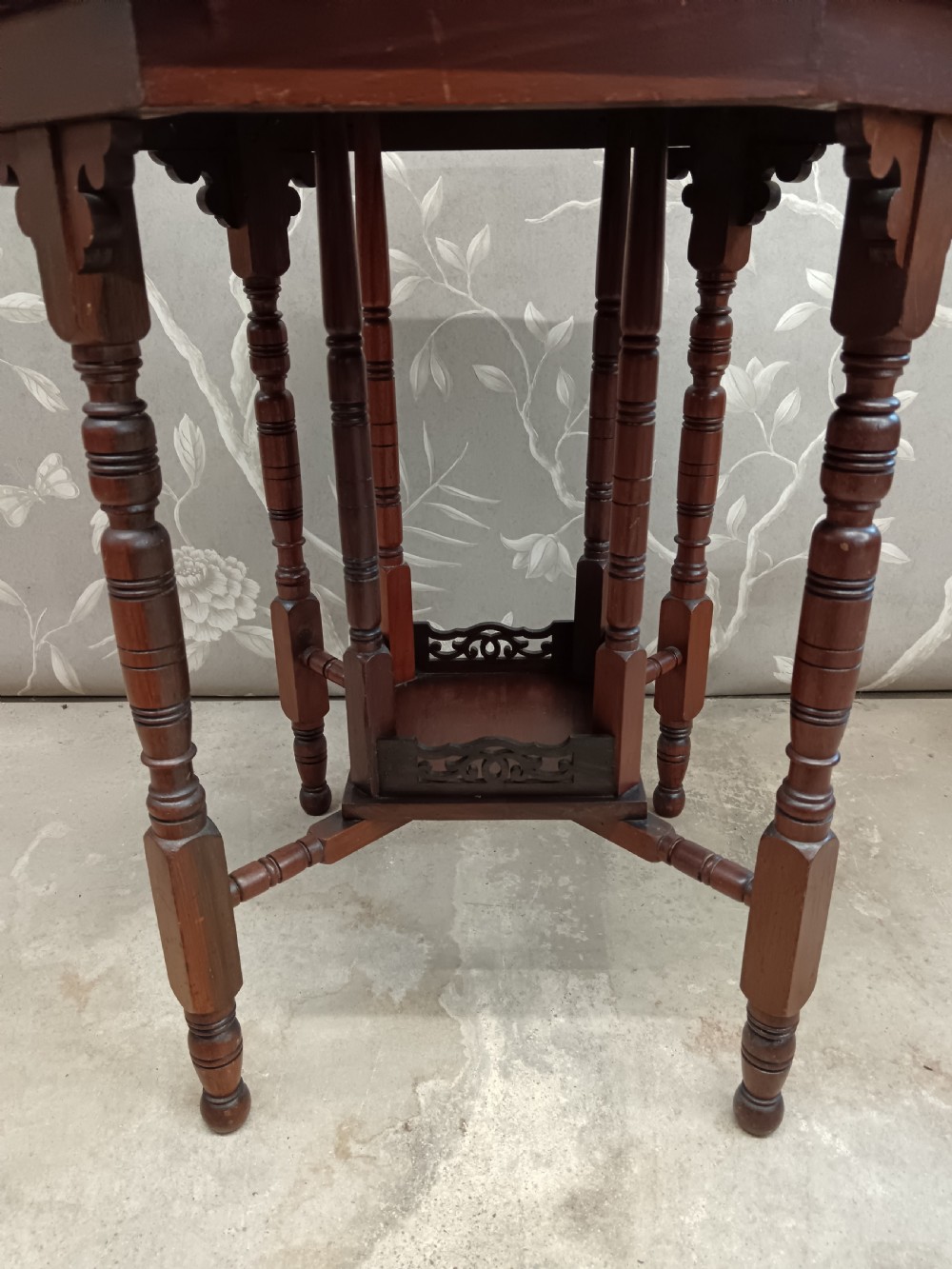 An octagonal dark walnut side table featuring turned legs, a lower shelf with decorative carved fretwork, and an eight-sided bevelled top. View III