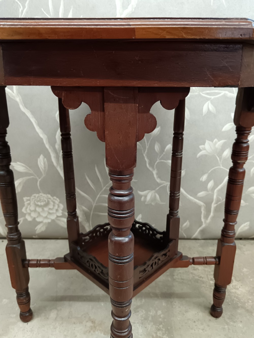 An octagonal dark walnut side table featuring turned legs, a lower shelf with decorative carved fretwork, and an eight-sided bevelled top. View V