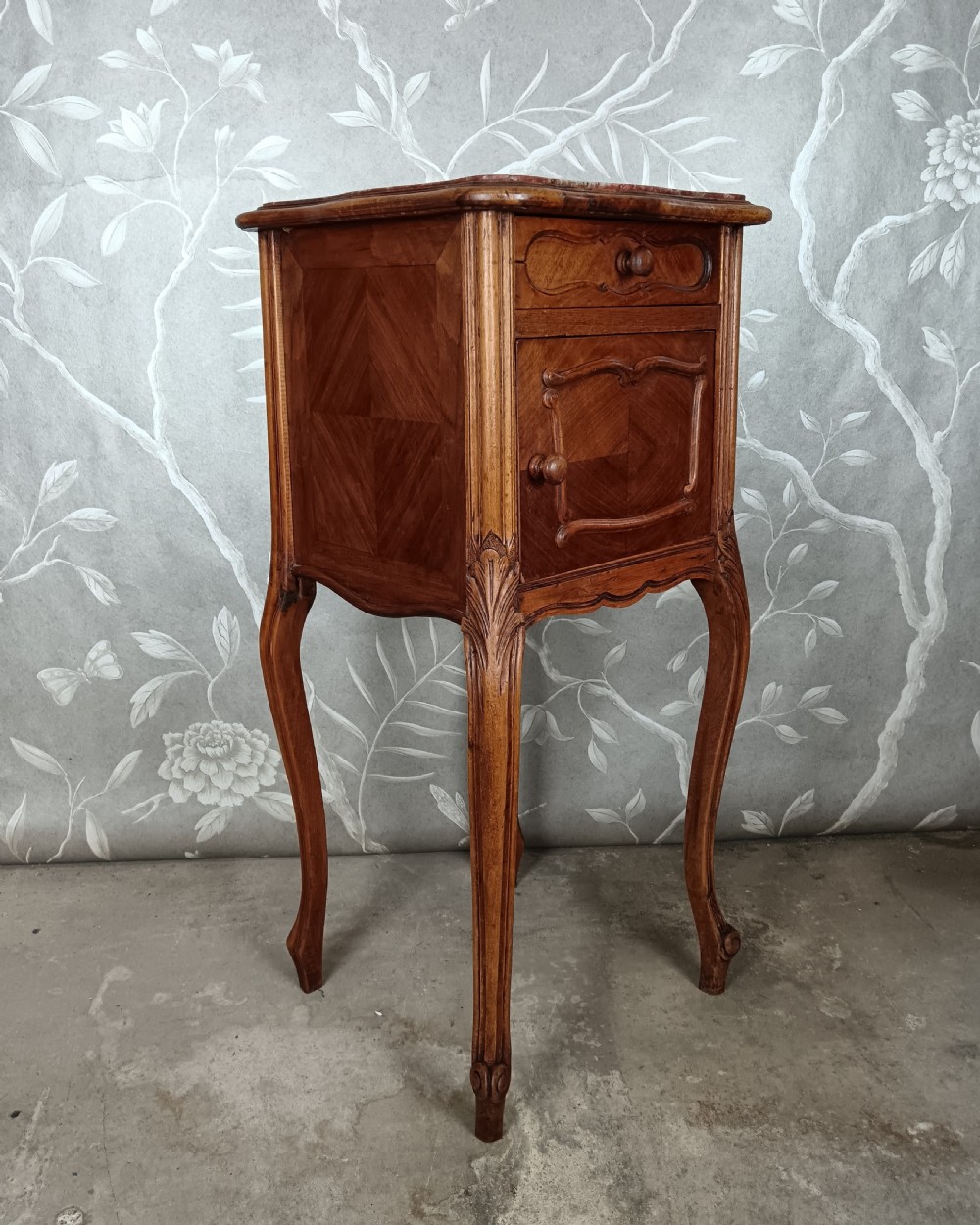 A tall French bedside cupboard crafted from warm brown wood with slim cabriole legs, parquetry panels, a single top drawer, and a lower cabinet door. View III