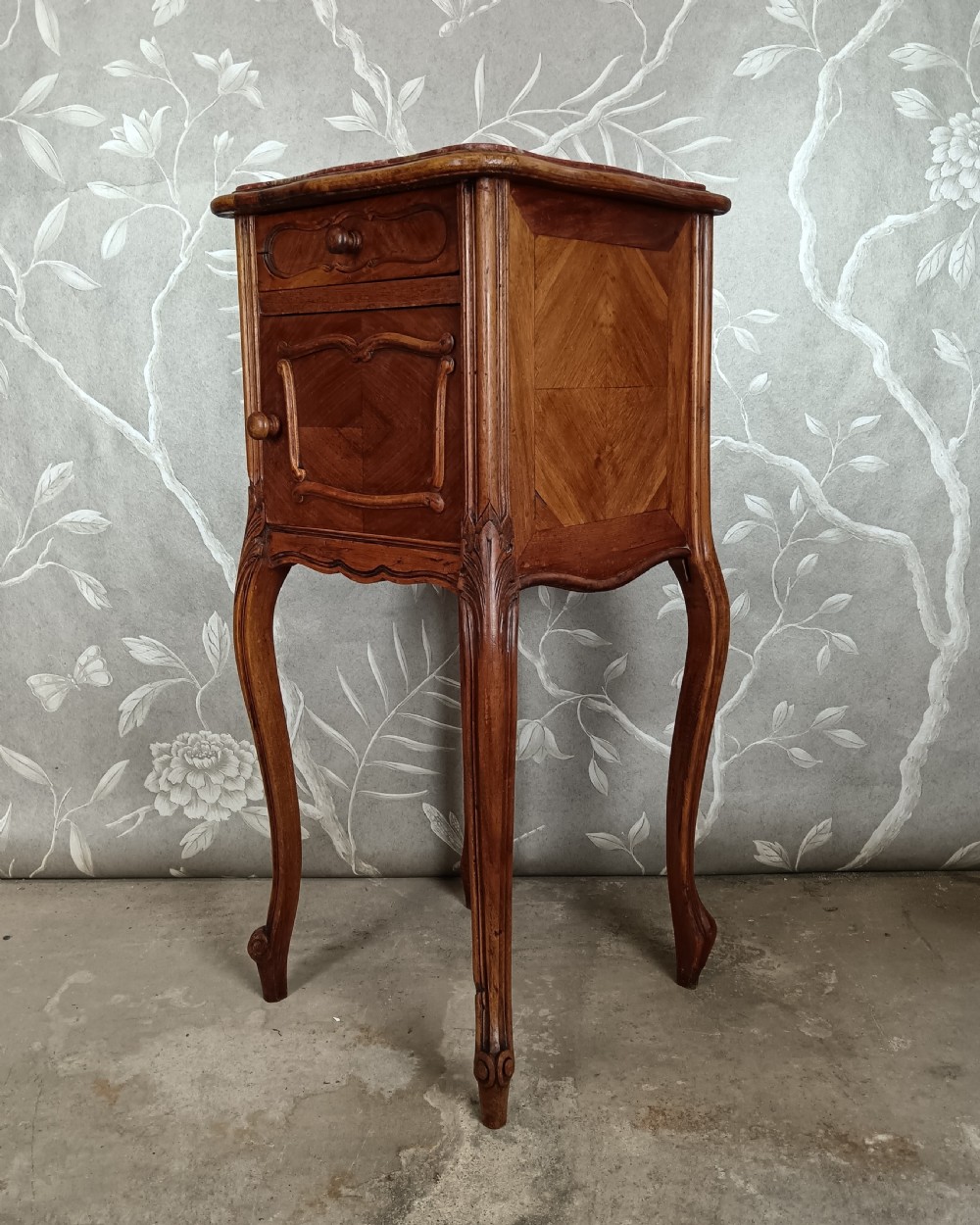 A tall French bedside cupboard crafted from warm brown wood with slim cabriole legs, parquetry panels, a single top drawer, and a lower cabinet door. View VIII