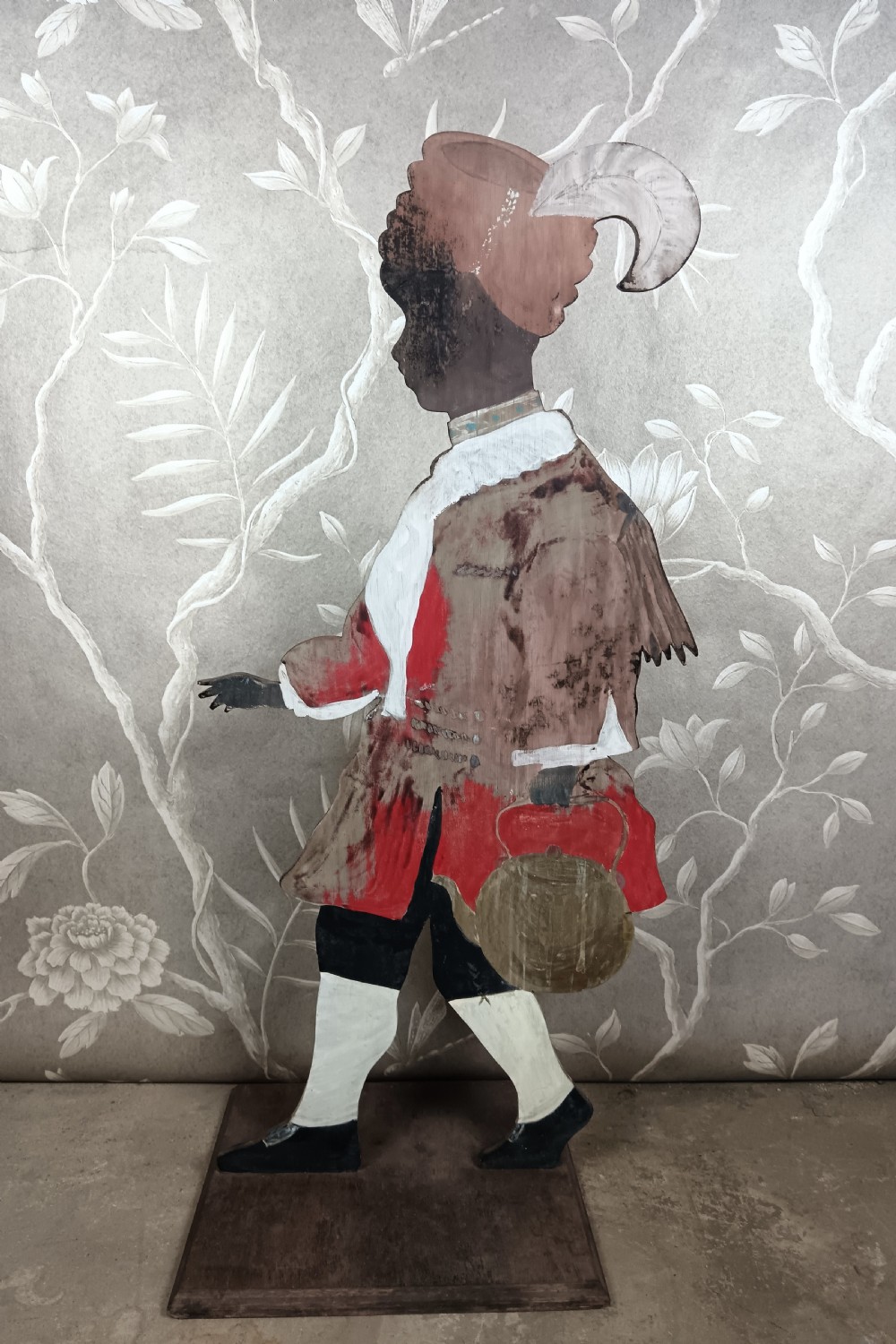 An early twentieth-century painted wooden dummy board figure depicting a man in a red coat and feathered hat holding a kettle. View V