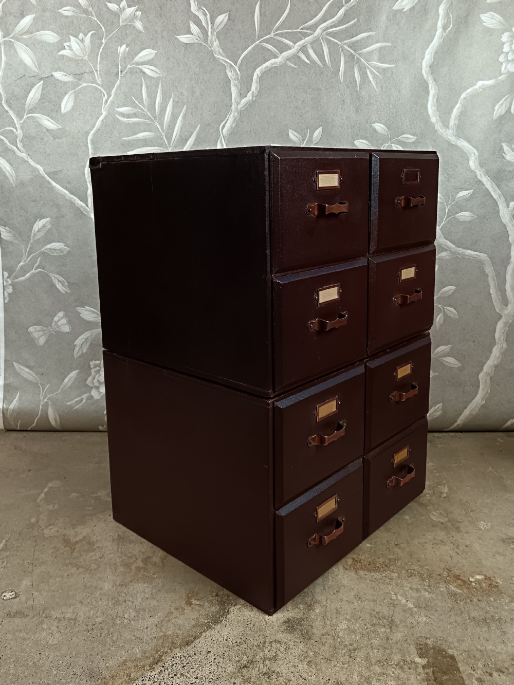 A dark brown modular card index filing cabinet featuring multiple drawers with copper handles and metal label holders. View IV