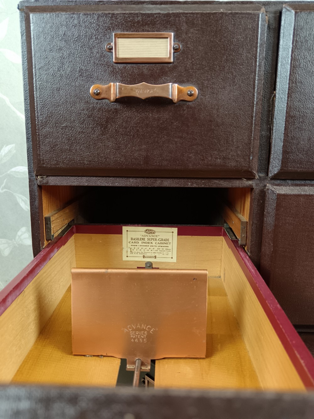 A dark brown modular card index filing cabinet featuring multiple drawers with copper handles and metal label holders. View IX