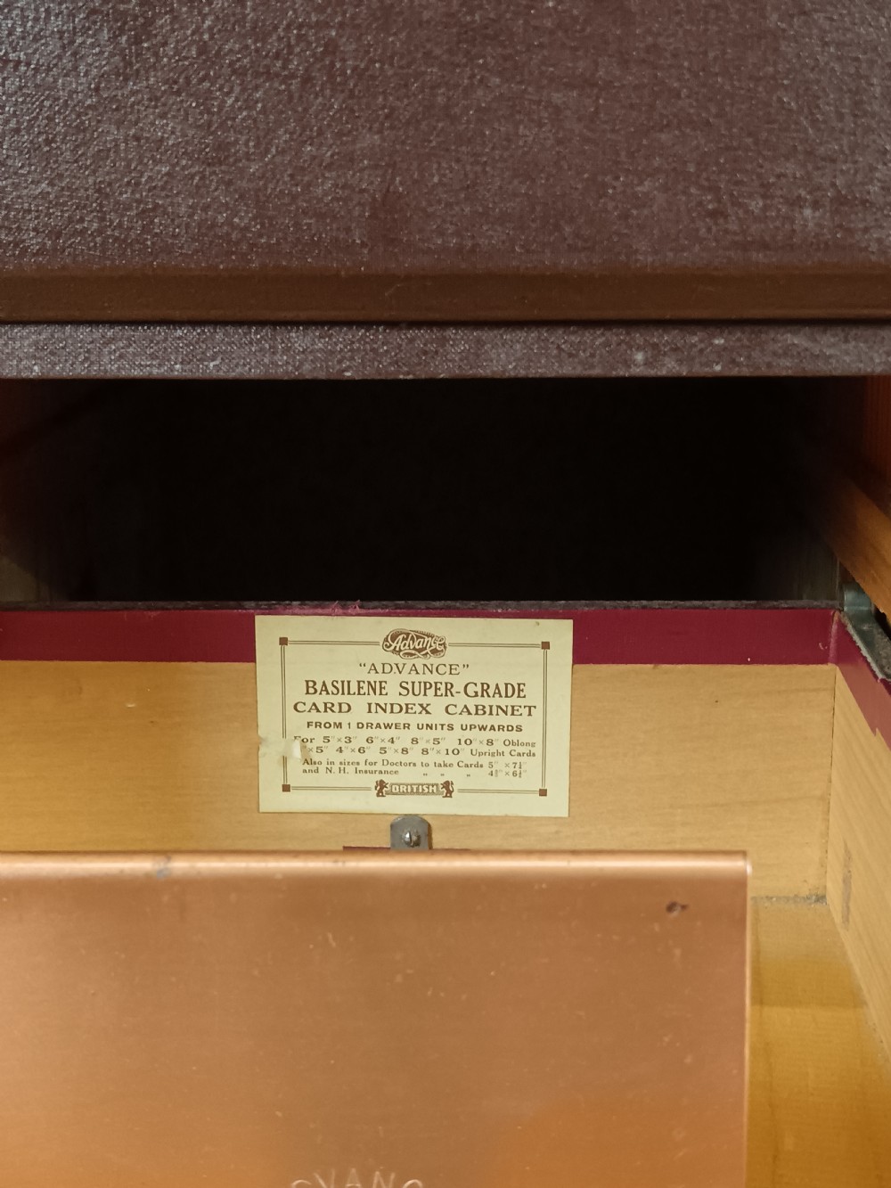 A dark brown modular card index filing cabinet featuring multiple drawers with copper handles and metal label holders. View X
