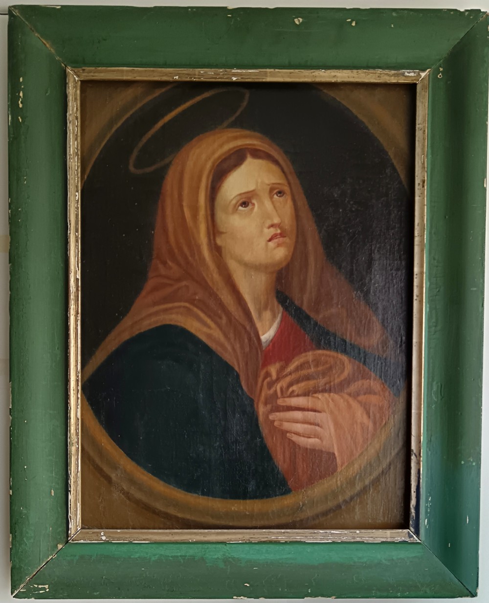 A 19th-century oil painting on canvas depicting the Virgin Mary looking upwards, set inside an oval painted spandrel and framed within a painted green wooden frame.