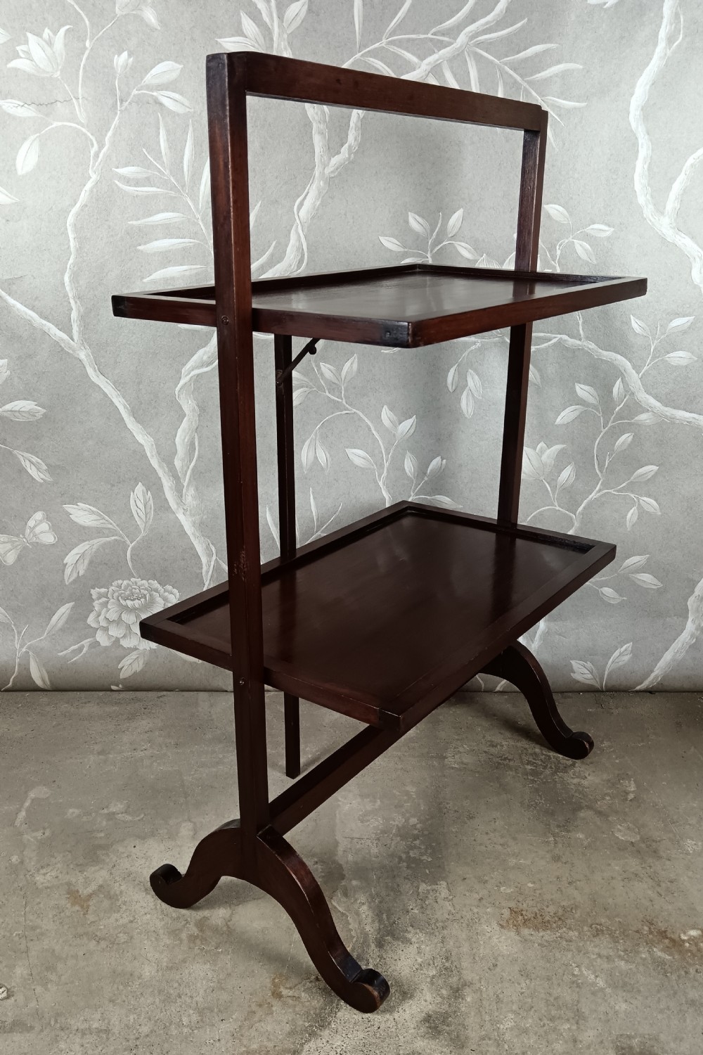 A dark mahogany two-tier folding dumb waiter with rectangular tray surfaces, upper carrying handle, and splayed legs. View IV