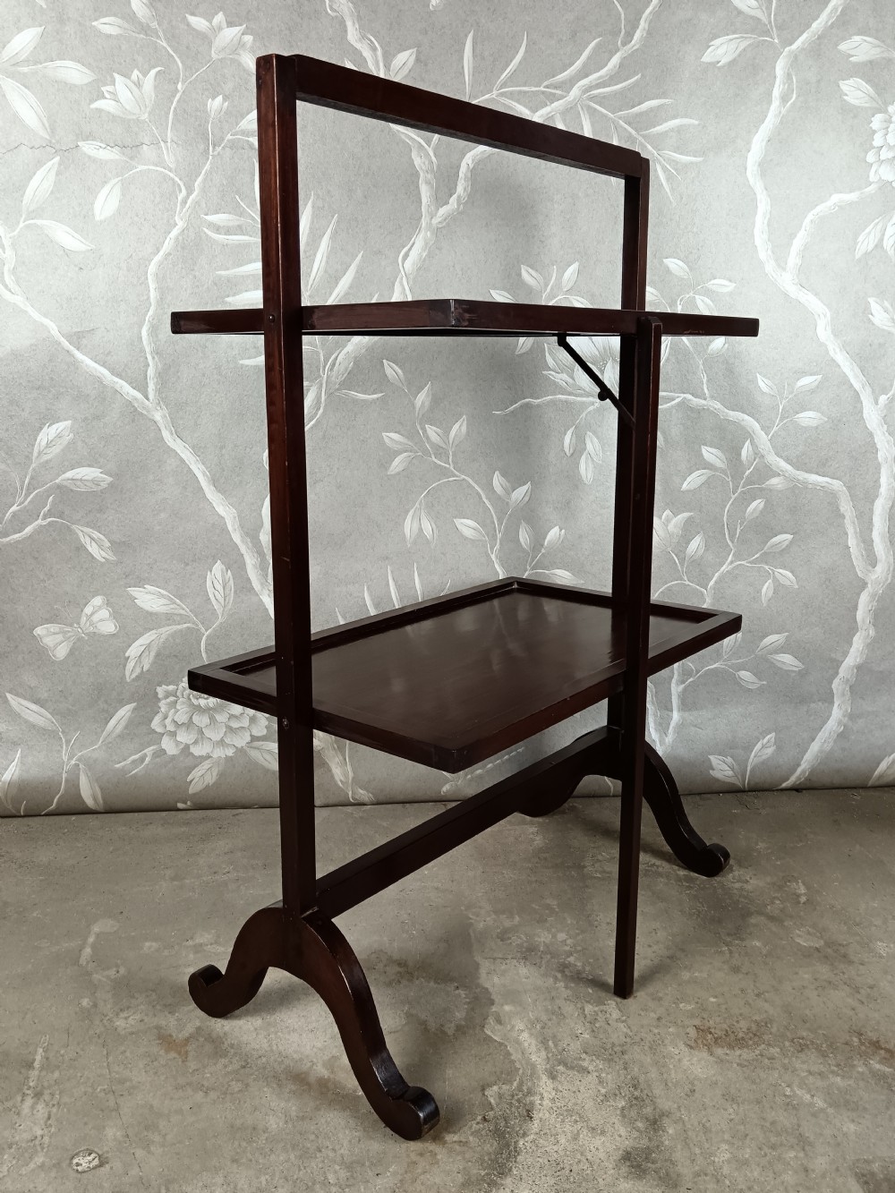 A dark mahogany two-tier folding dumb waiter with rectangular tray surfaces, upper carrying handle, and splayed legs. View VIII