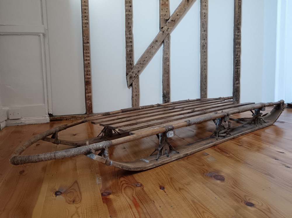 An antique Nansen-style polar expedition sledge constructed from timber slats bound with cordage on curved wooden runners. View III