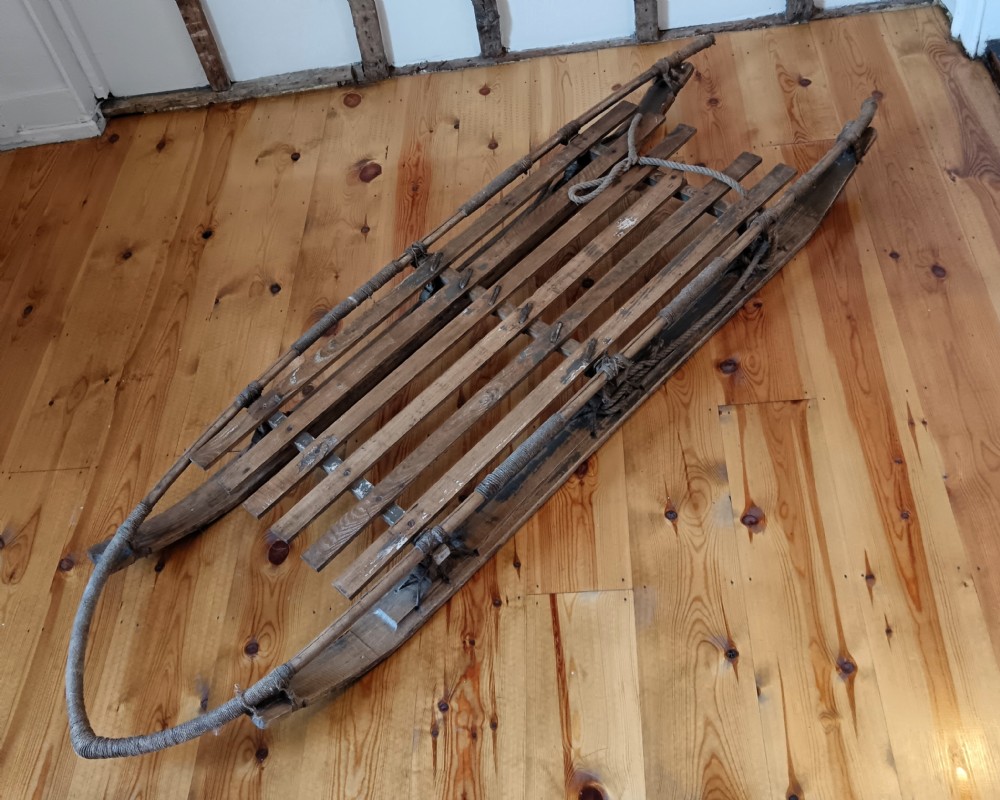 An antique Nansen-style polar expedition sledge constructed from timber slats bound with cordage on curved wooden runners.