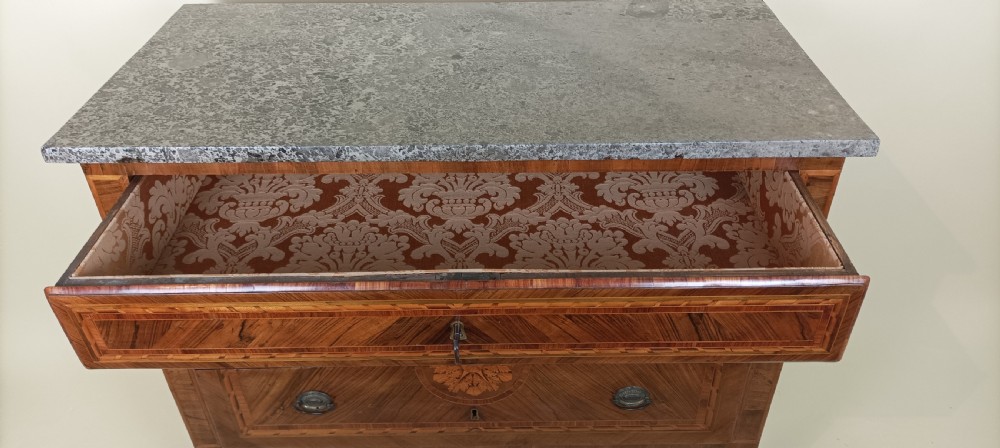 An eighteenth-century Italian Neoclassical marquetry commode with three drawers, geometric timber inlays, a grey marble top, and tapered square legs. View VI