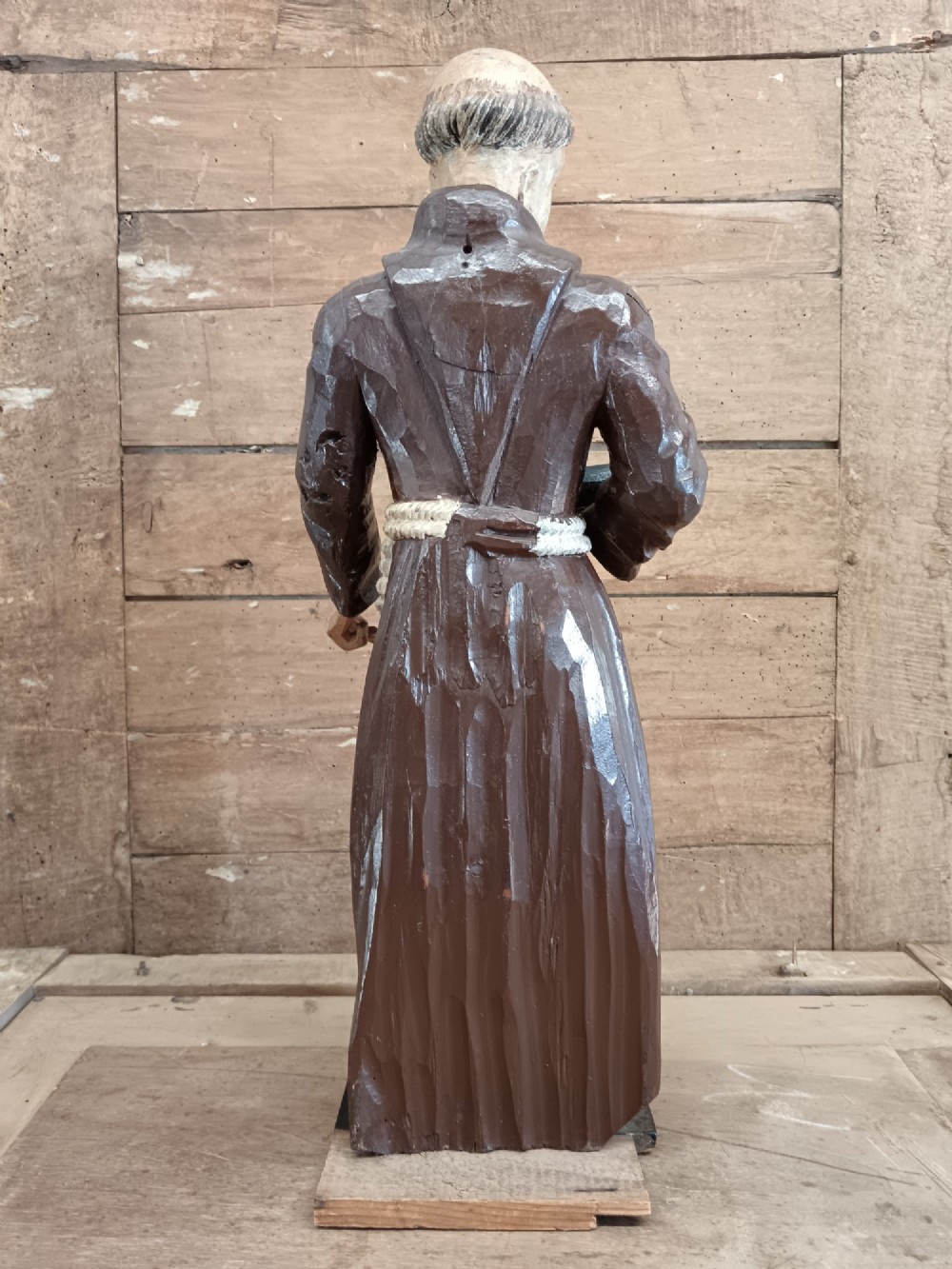 An antique carved wooden figure depicting Saint Anthony wearing a dark brown habit and holding a book. View XI