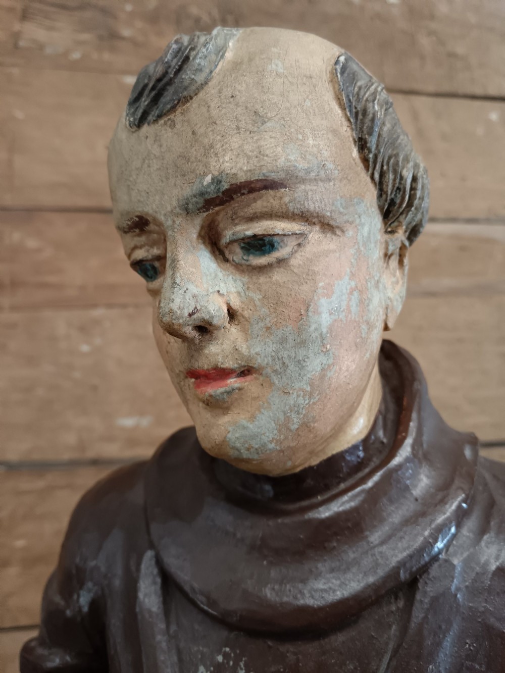 An antique carved wooden figure depicting Saint Anthony wearing a dark brown habit and holding a book. View XII