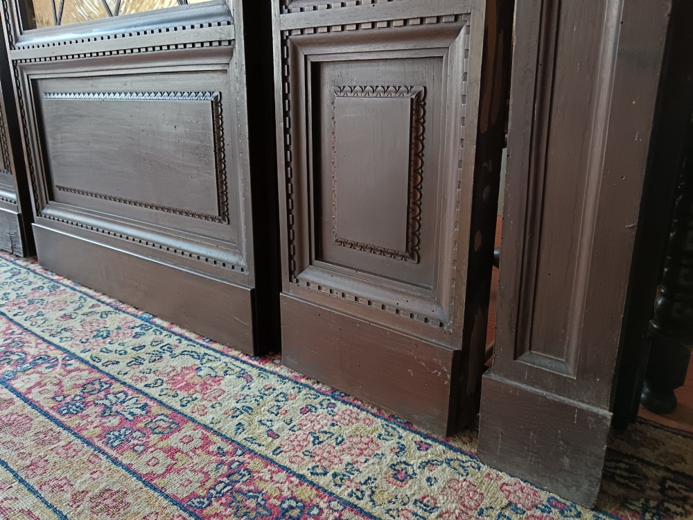 An antique dark wood vestibule doorway featuring a central arched leaded glass door flanked by two slender side lights and classic fluted columns. View V