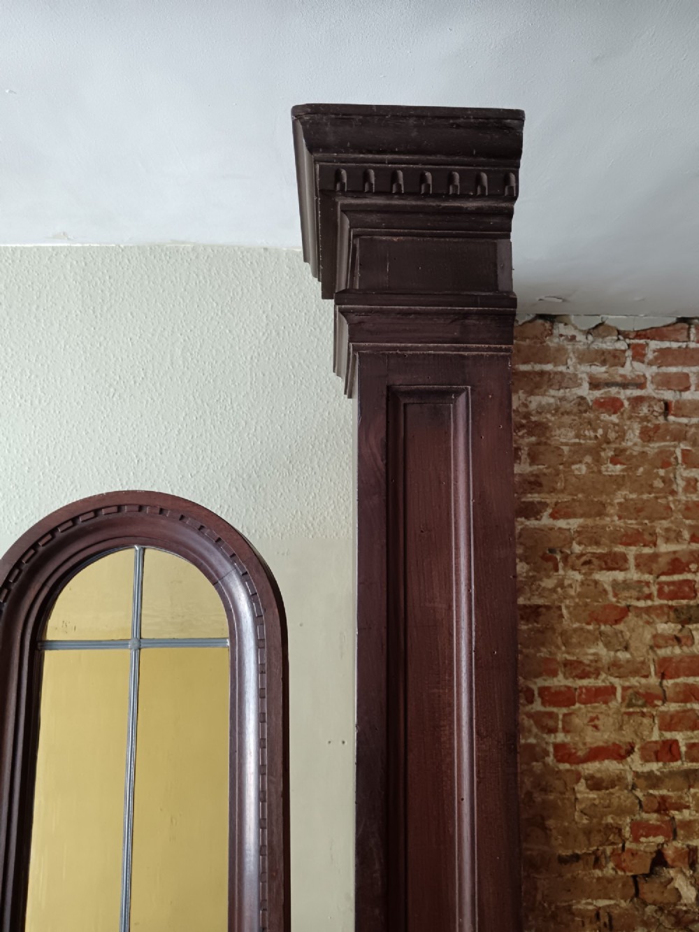 An antique dark wood vestibule doorway featuring a central arched leaded glass door flanked by two slender side lights and classic fluted columns. View VI