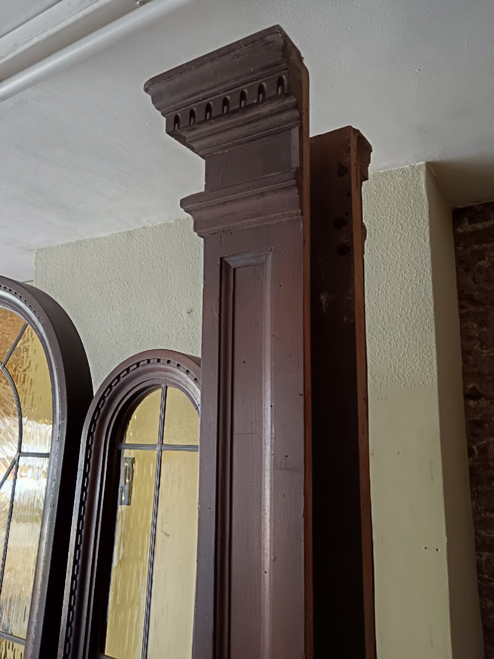 An antique dark wood vestibule doorway featuring a central arched leaded glass door flanked by two slender side lights and classic fluted columns. View VII