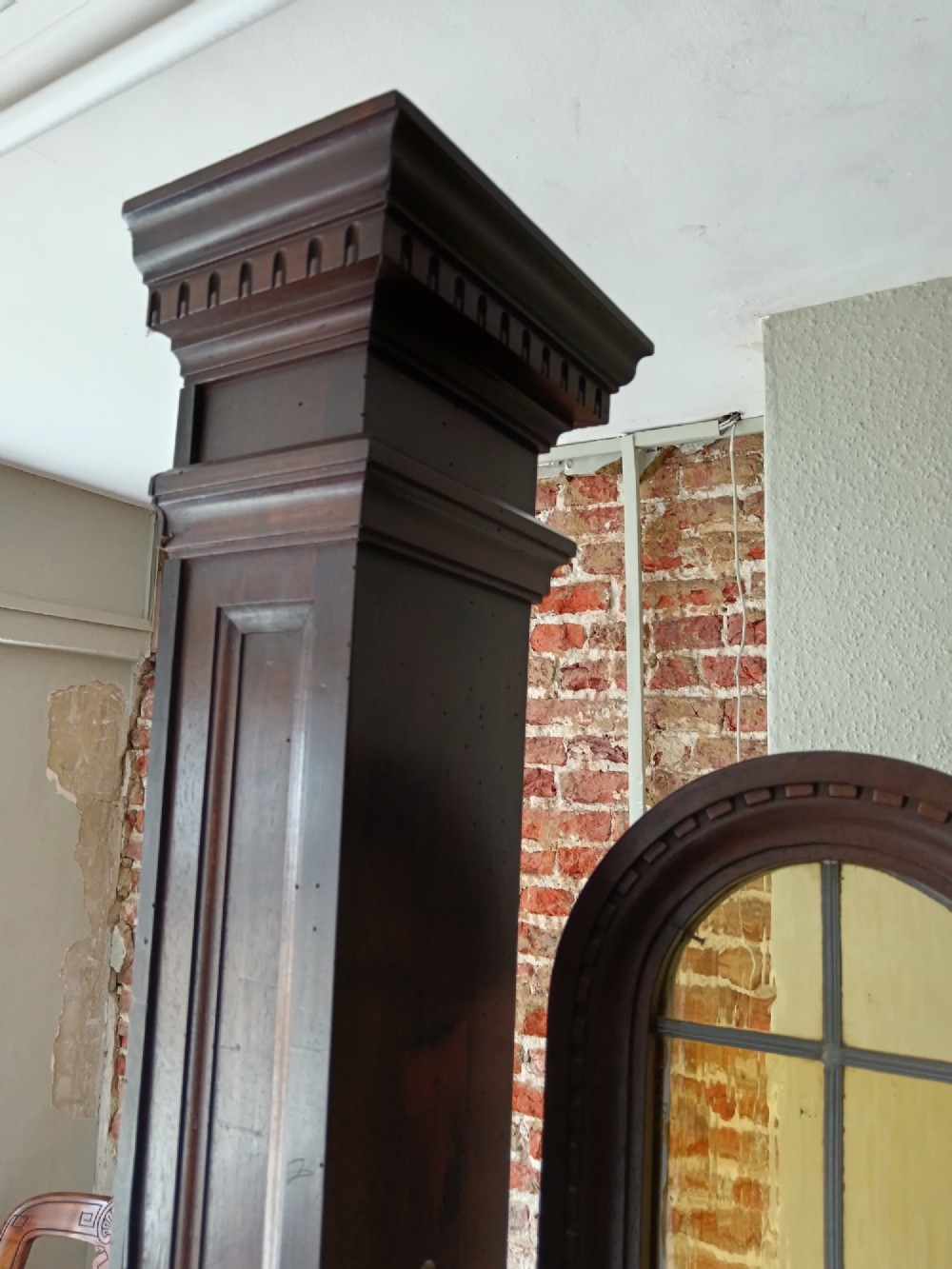 An antique dark wood vestibule doorway featuring a central arched leaded glass door flanked by two slender side lights and classic fluted columns. View VIII