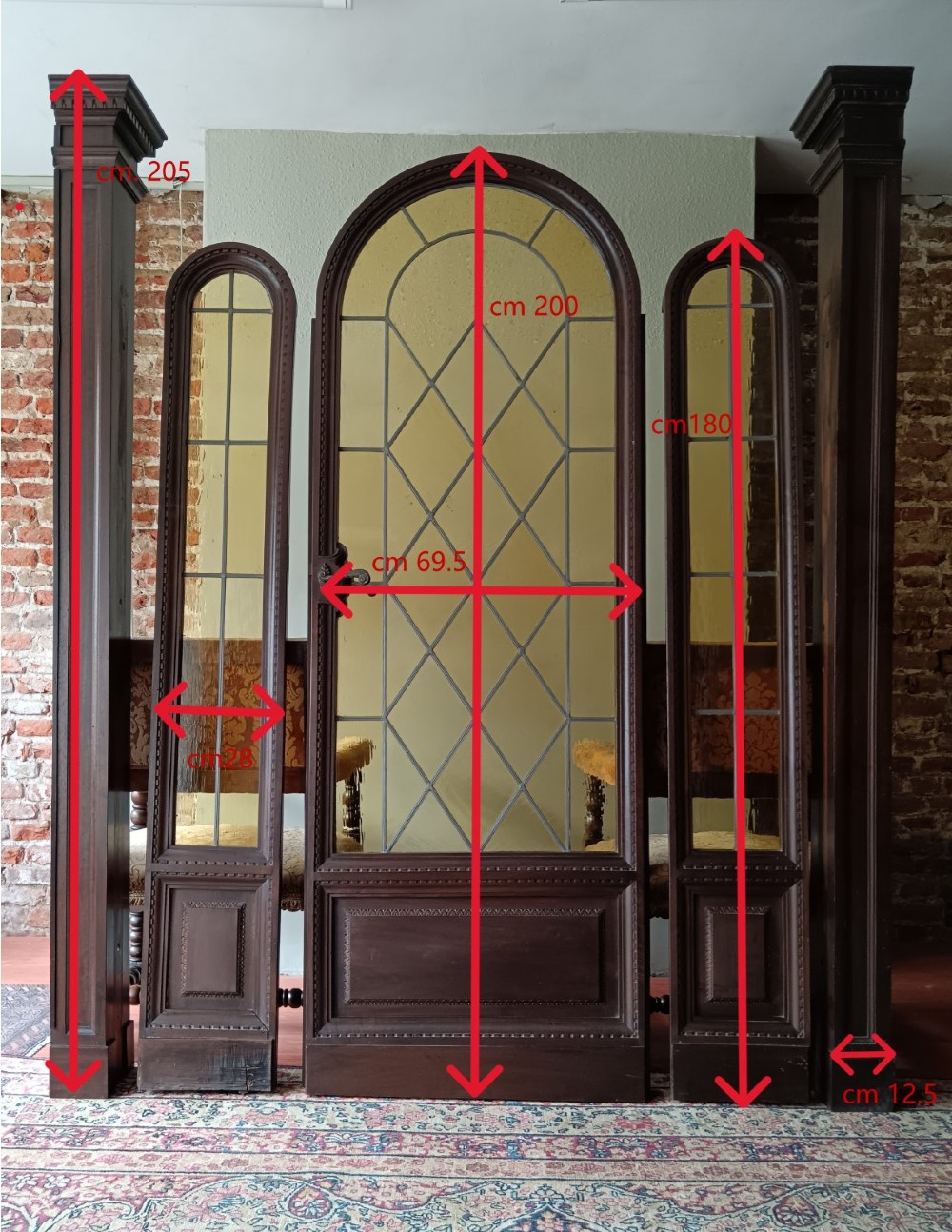 An antique dark wood vestibule doorway featuring a central arched leaded glass door flanked by two slender side lights and classic fluted columns. View XIII