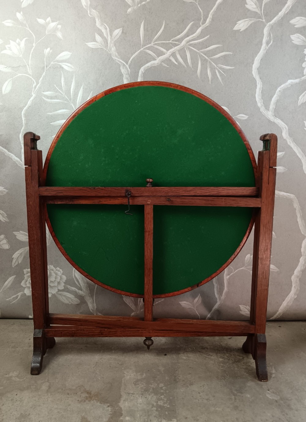 An antique oak folding card table with a circular reversible top supported by an interlocking wooden base. View III