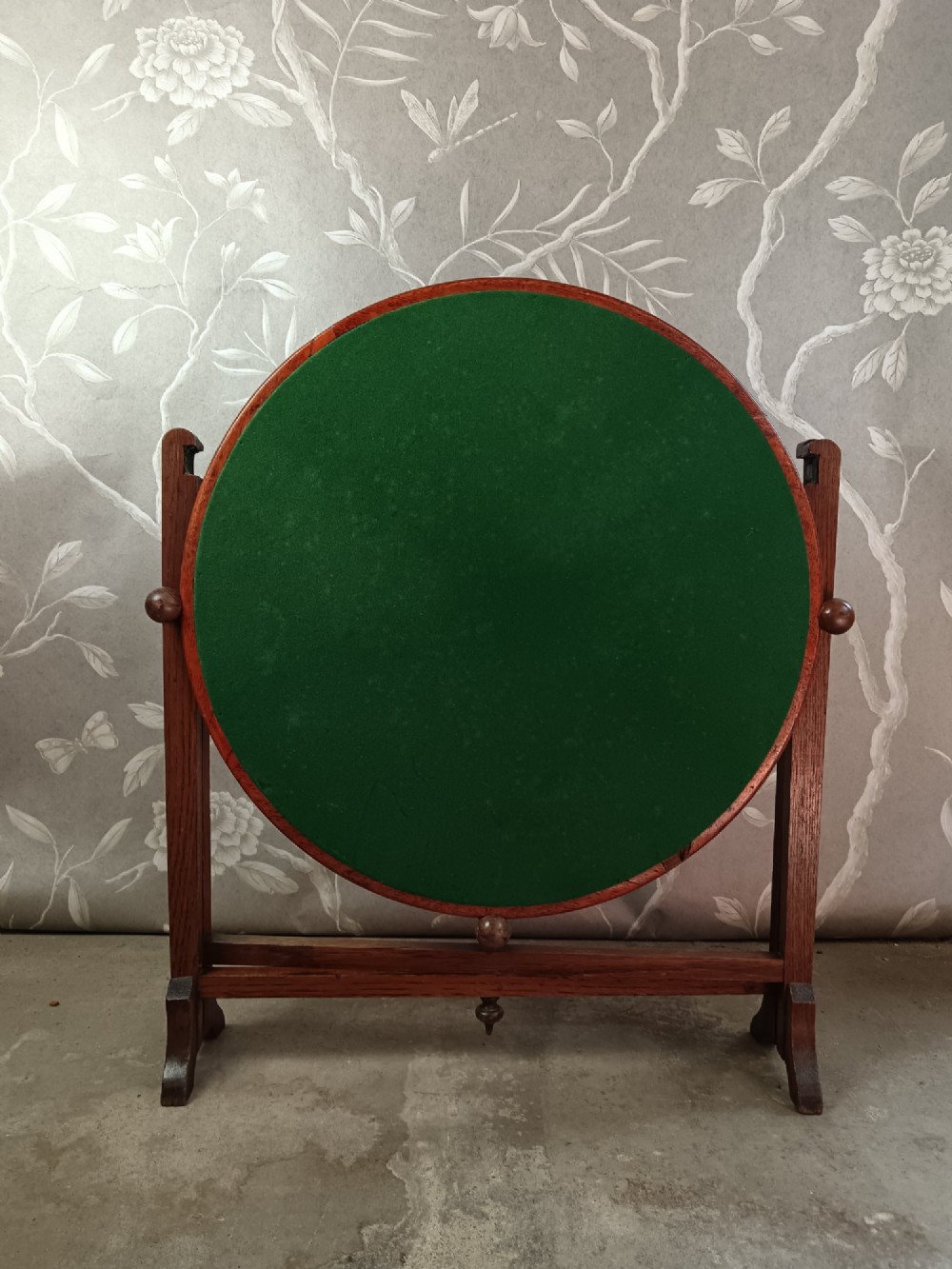 An antique oak folding card table with a circular reversible top supported by an interlocking wooden base. View V