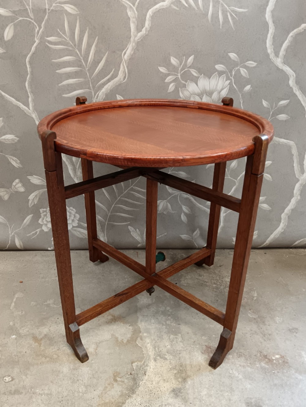 An antique oak folding card table with a circular reversible top supported by an interlocking wooden base. View VII