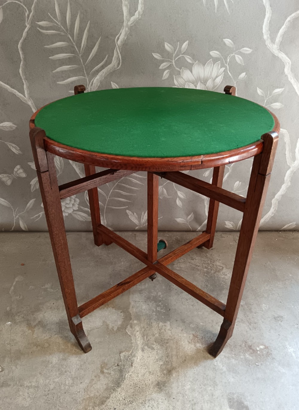 An antique oak folding card table with a circular reversible top supported by an interlocking wooden base. View VIII