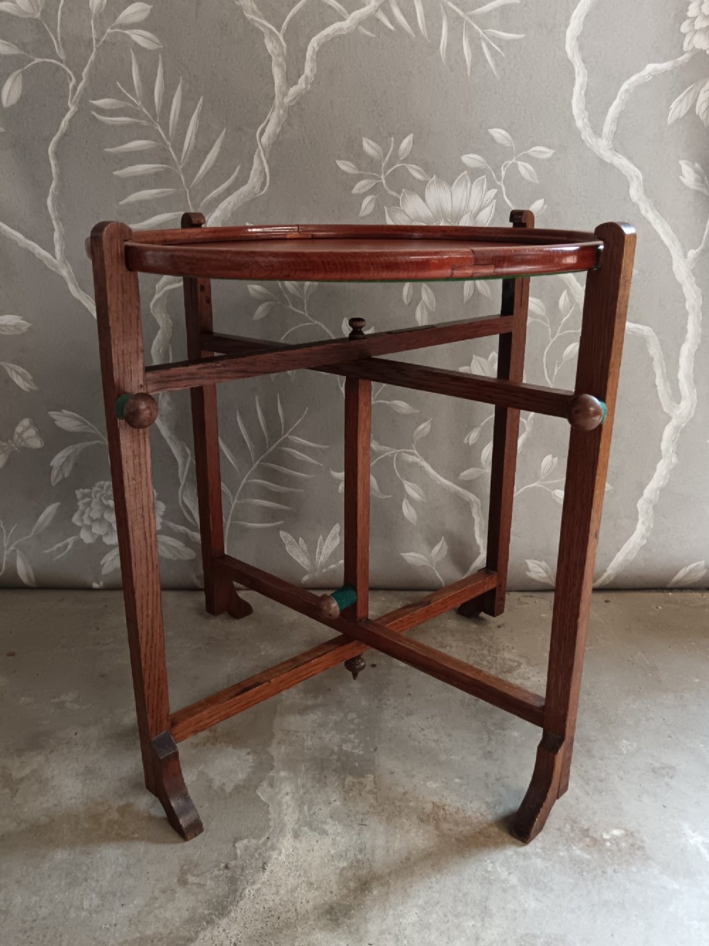 An antique oak folding card table with a circular reversible top supported by an interlocking wooden base. View X