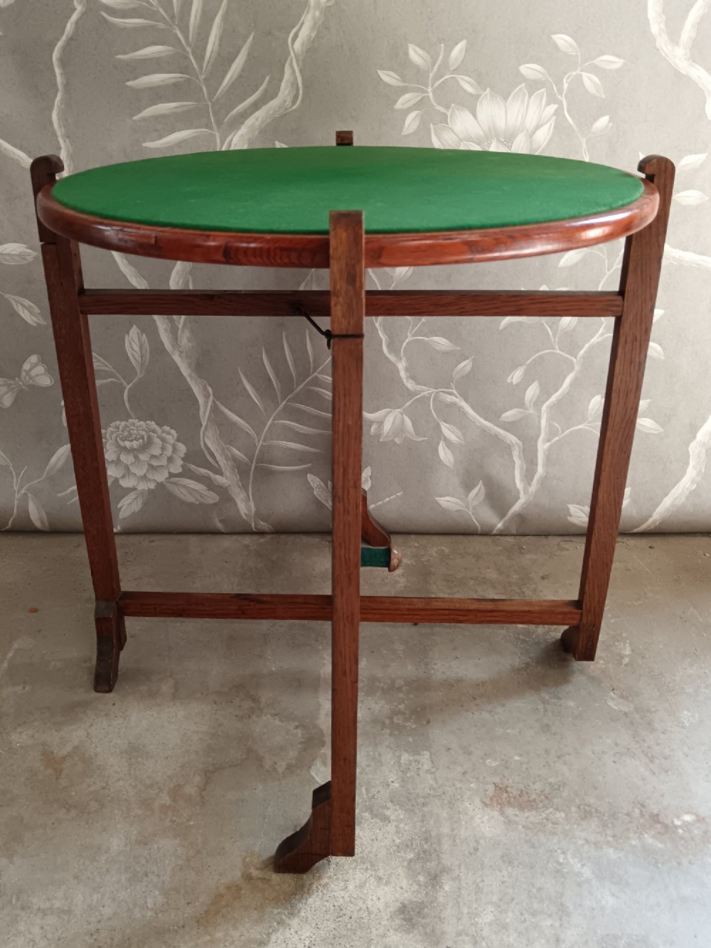 An antique oak folding card table with a circular reversible top supported by an interlocking wooden base. View XI