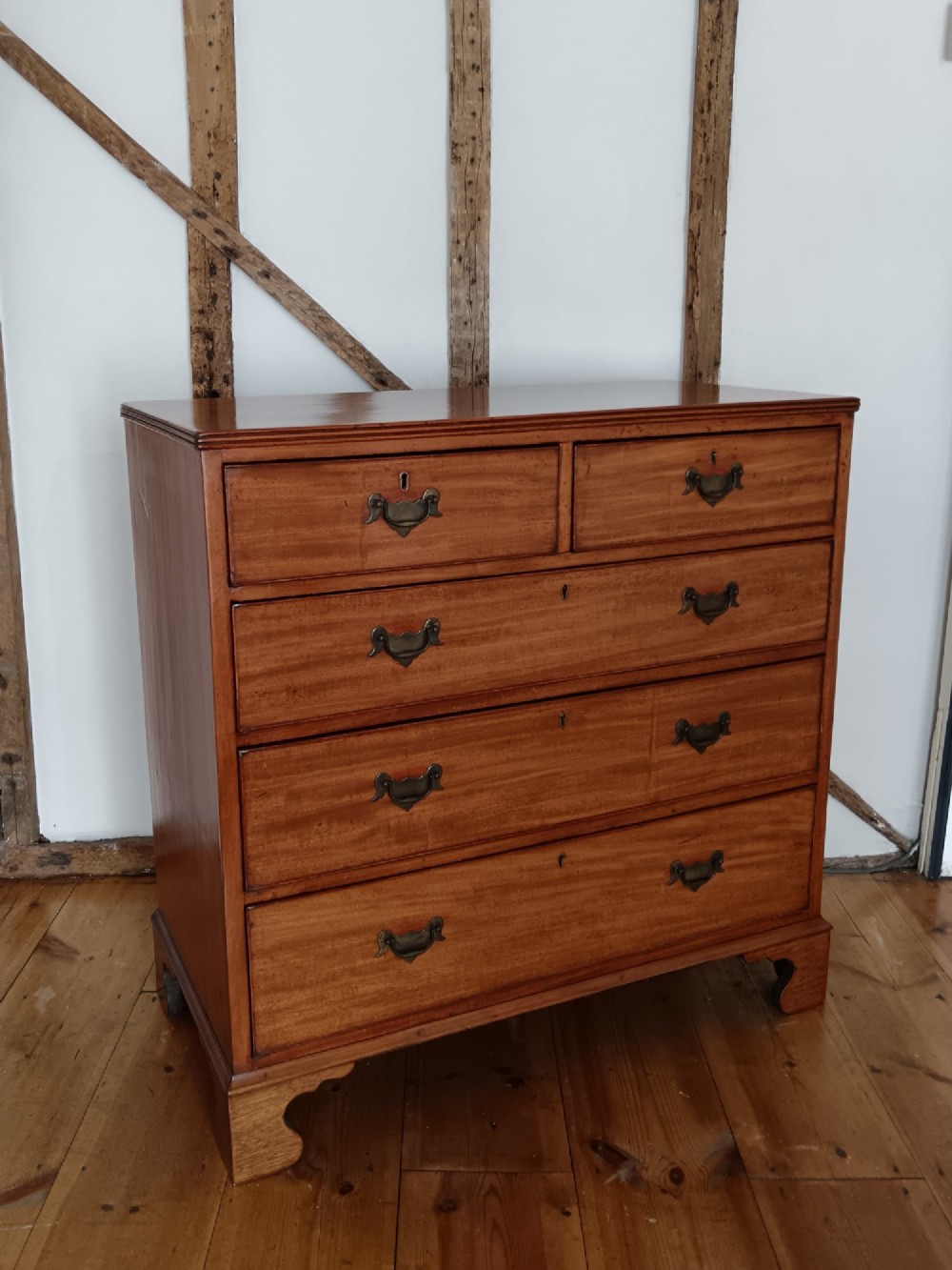 A Georgian mahogany chest of drawers featuring two short drawers above three full-width graduated drawers with brass drop handles and bracket feet.