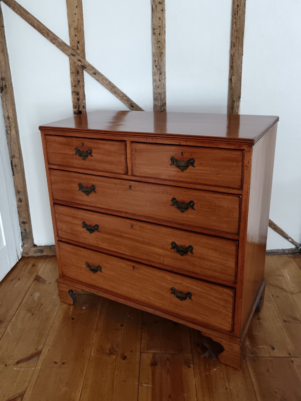 A Georgian mahogany chest of drawers featuring two short drawers above three full-width graduated drawers with brass drop handles and bracket feet. View II
