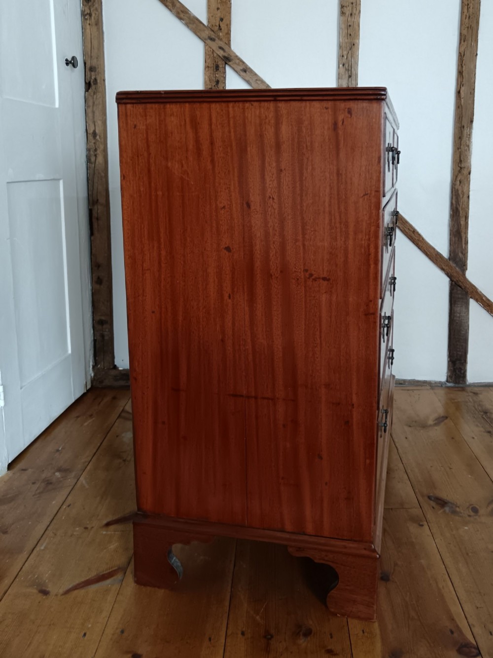 A Georgian mahogany chest of drawers featuring two short drawers above three full-width graduated drawers with brass drop handles and bracket feet. View IV