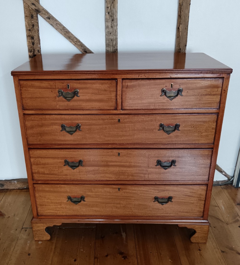 A Georgian mahogany chest of drawers featuring two short drawers above three full-width graduated drawers with brass drop handles and bracket feet. View VI