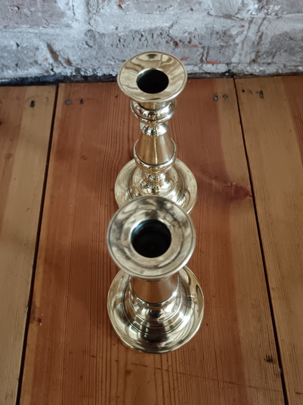 A pair of polished turned brass candlesticks featuring circular stepped bases and baluster stems. View VI