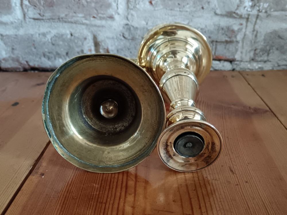A pair of polished turned brass candlesticks featuring circular stepped bases and baluster stems. View VIII