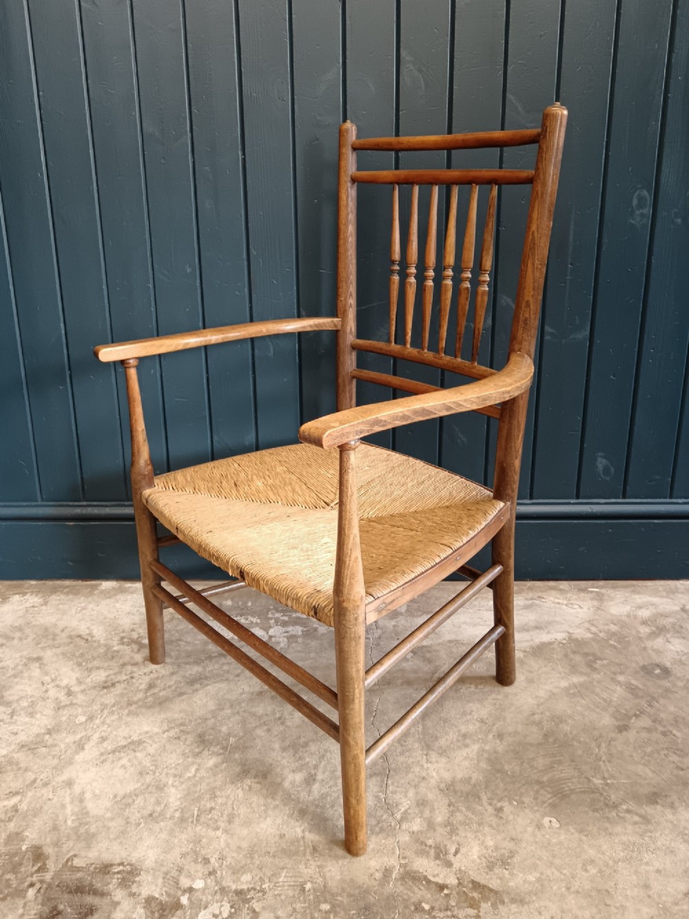 A late 19th-century Arts and Crafts Sussex armchair with a spindle backrest, curved armrests, turned legs, and a natural rush seat. View III