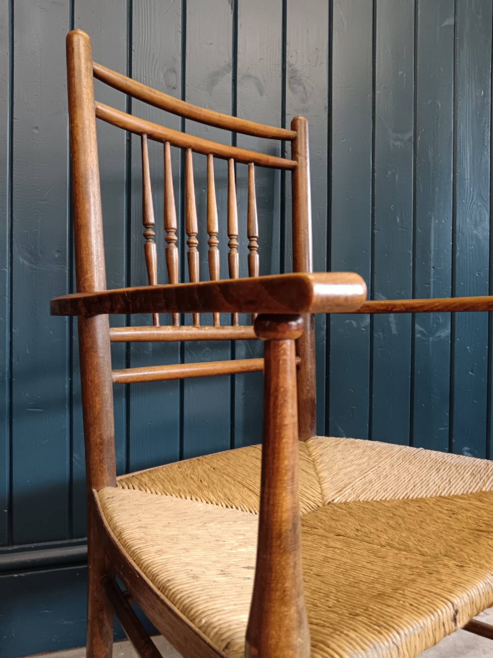 A late 19th-century Arts and Crafts Sussex armchair with a spindle backrest, curved armrests, turned legs, and a natural rush seat. View XI