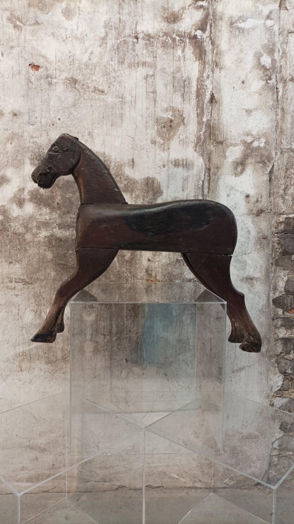 A hand-carved primitive wooden horse sculpture with a dark brown painted surface. View II