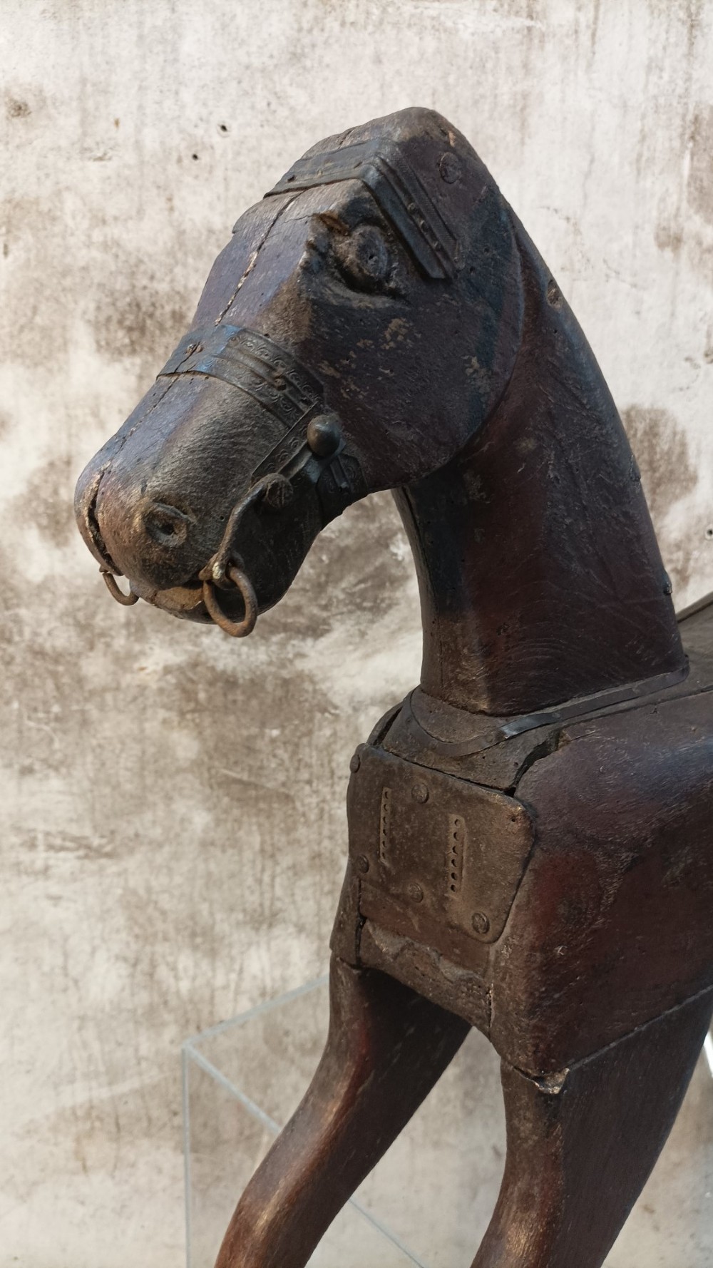 A hand-carved primitive wooden horse sculpture with a dark brown painted surface. View III