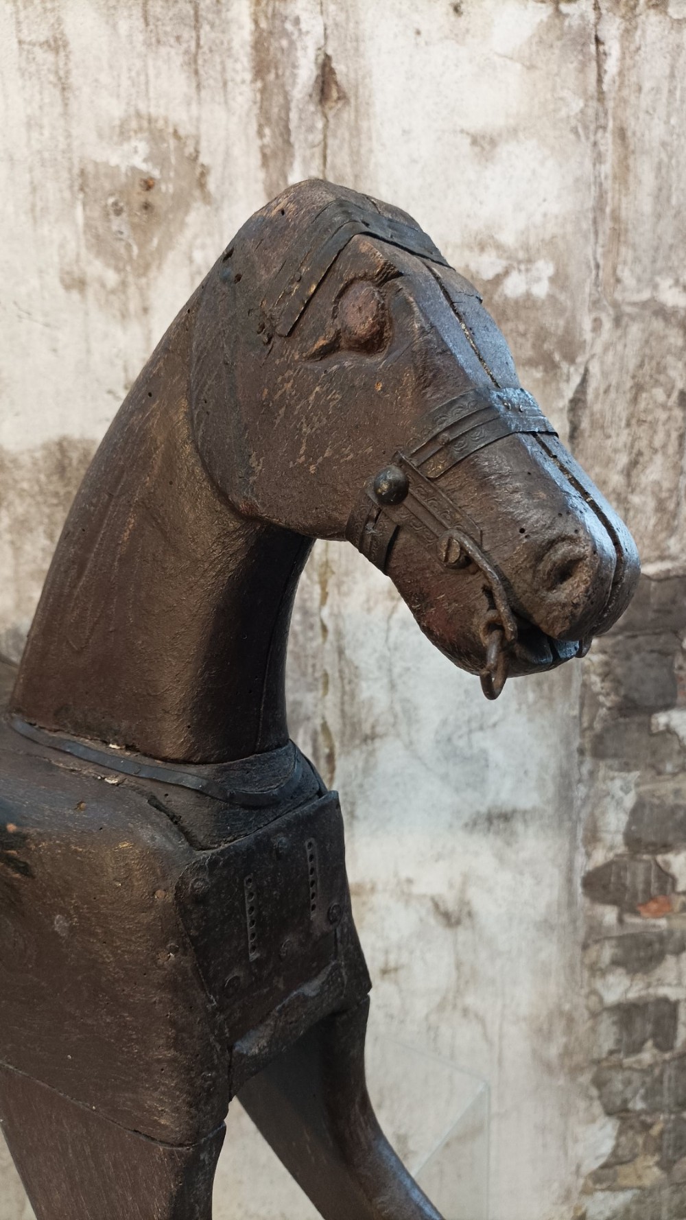 A hand-carved primitive wooden horse sculpture with a dark brown painted surface. View IV