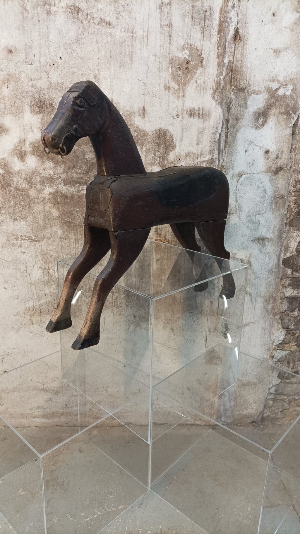 A hand-carved primitive wooden horse sculpture with a dark brown painted surface. View VI