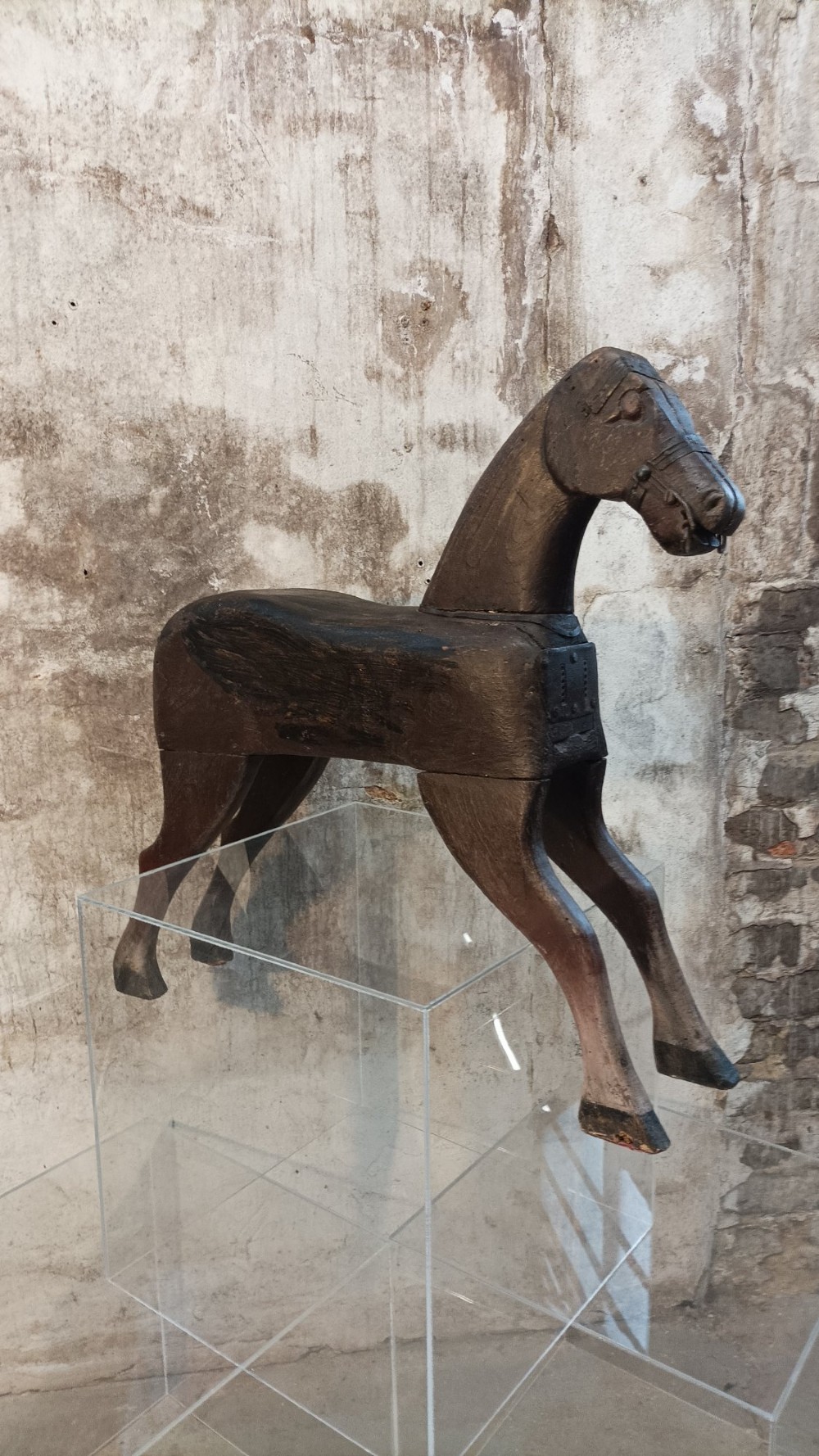 A hand-carved primitive wooden horse sculpture with a dark brown painted surface.
