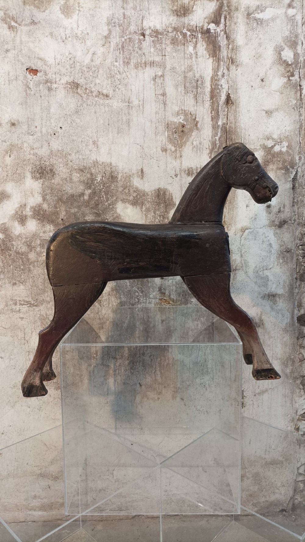 A hand-carved primitive wooden horse sculpture with a dark brown painted surface. View VIII