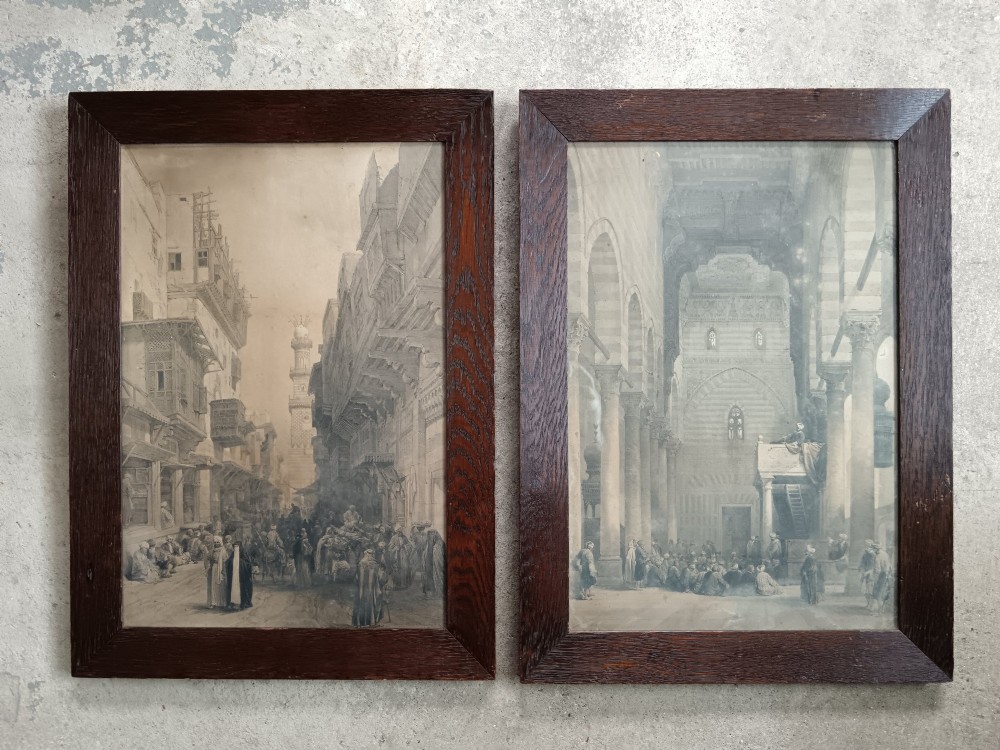 A pair of 19th-century sepia lithographs depicting architectural street and interior scenes of Cairo, mounted in dark oak frames. View II