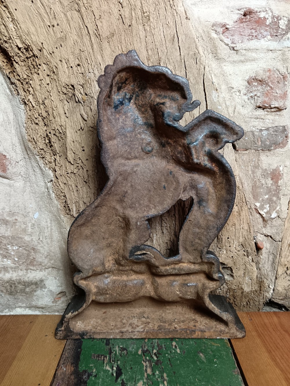 A black cast iron doorstop depicting a heraldic lion rampant seated on a decorated scrollwork base. View II