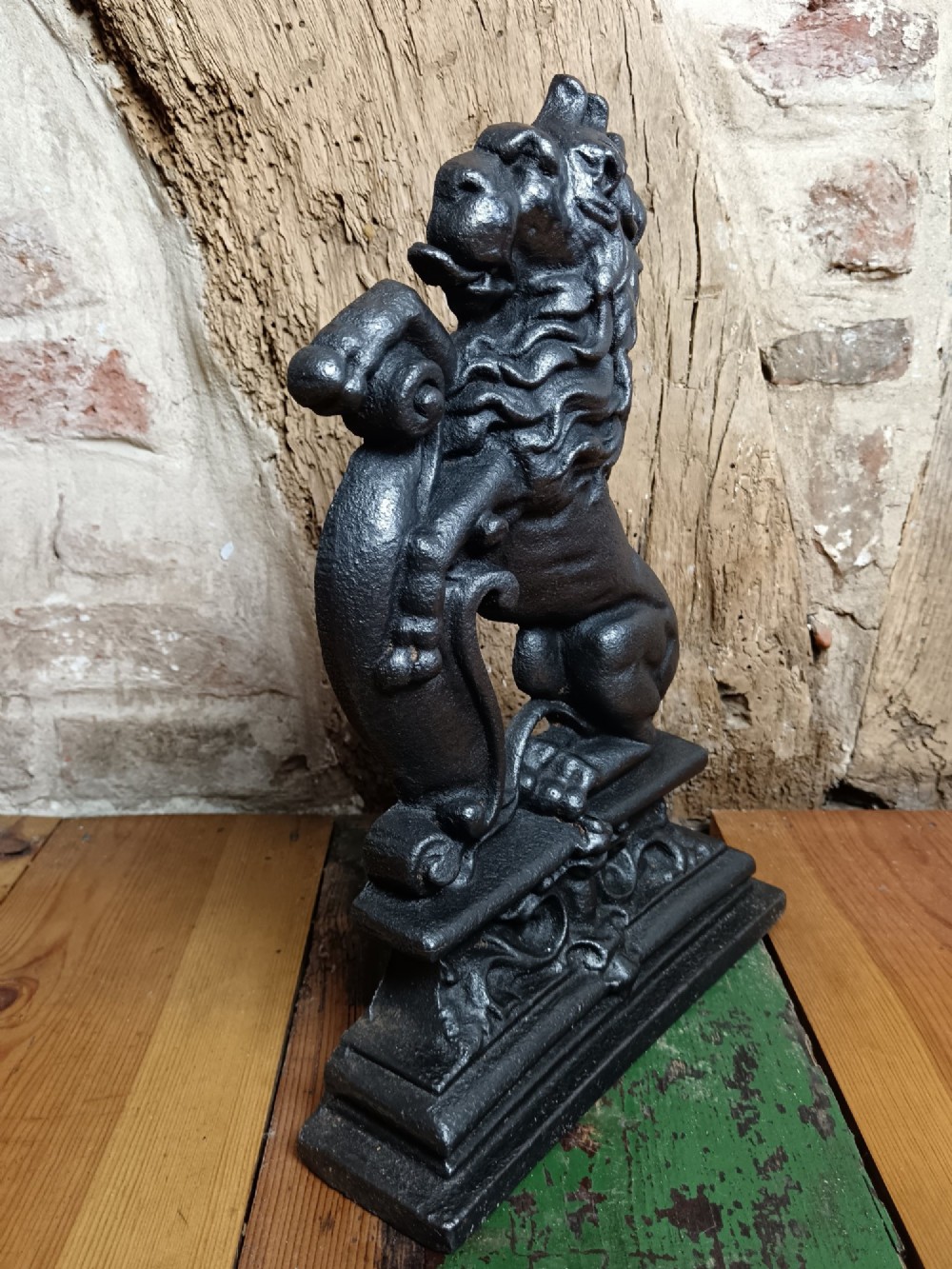 A black cast iron doorstop depicting a heraldic lion rampant seated on a decorated scrollwork base. View III