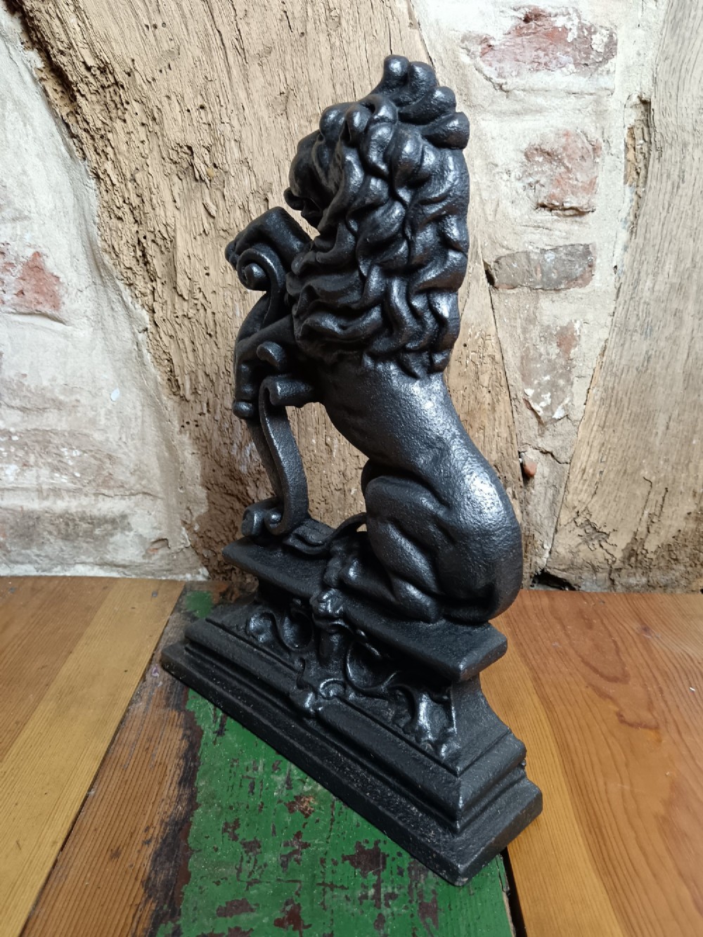 A black cast iron doorstop depicting a heraldic lion rampant seated on a decorated scrollwork base. View IV