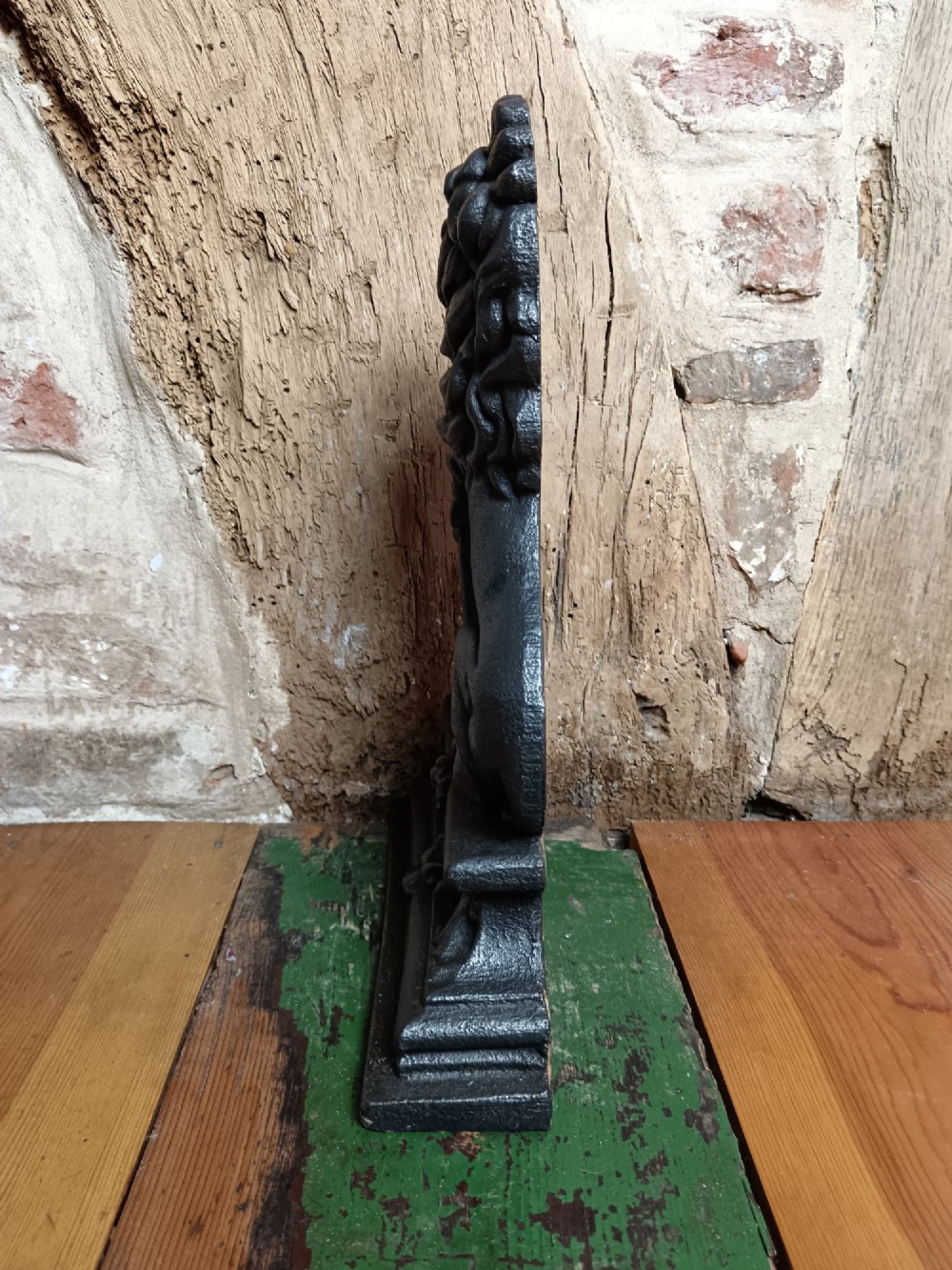 A black cast iron doorstop depicting a heraldic lion rampant seated on a decorated scrollwork base. View V