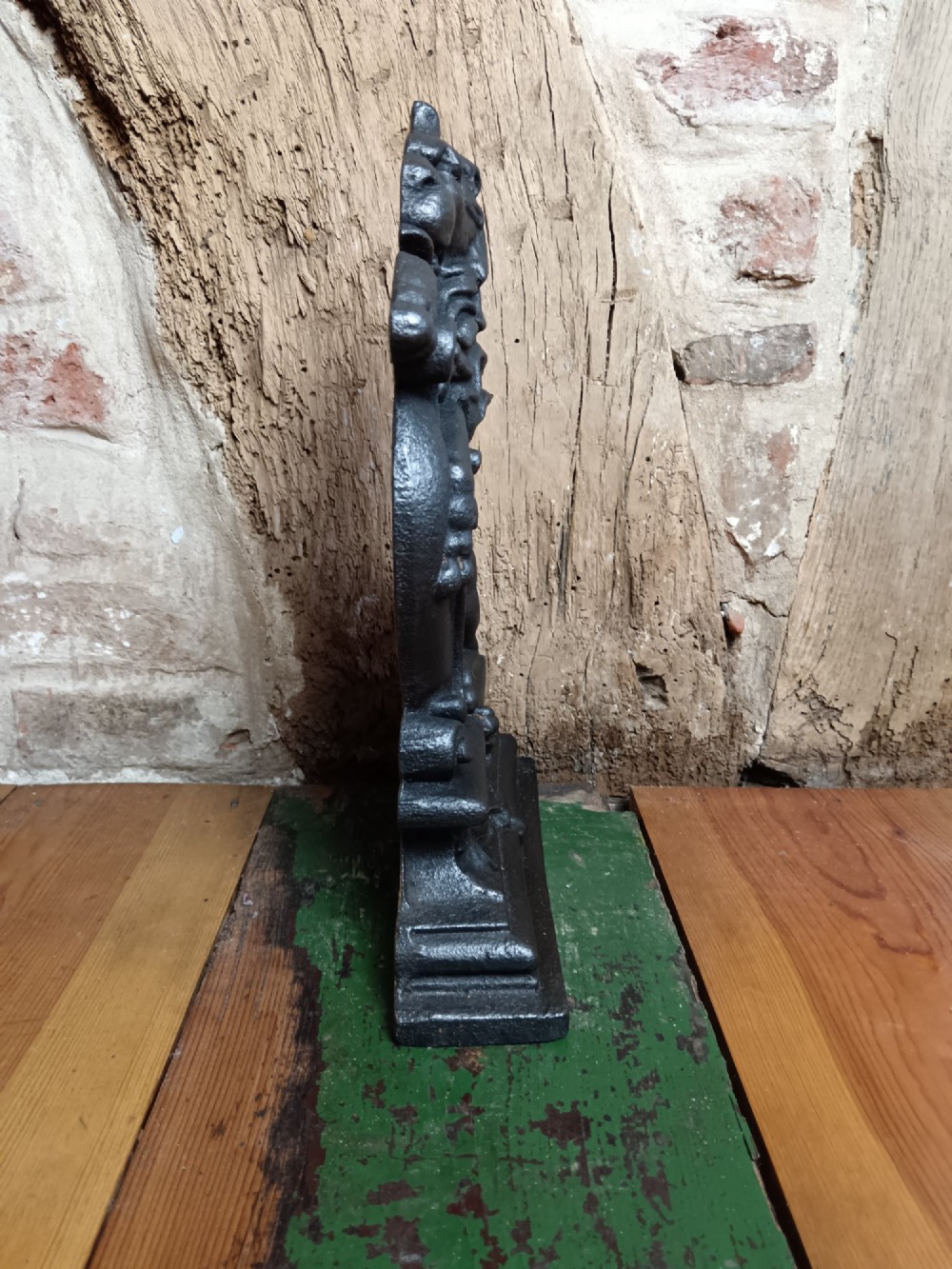 A black cast iron doorstop depicting a heraldic lion rampant seated on a decorated scrollwork base. View VI