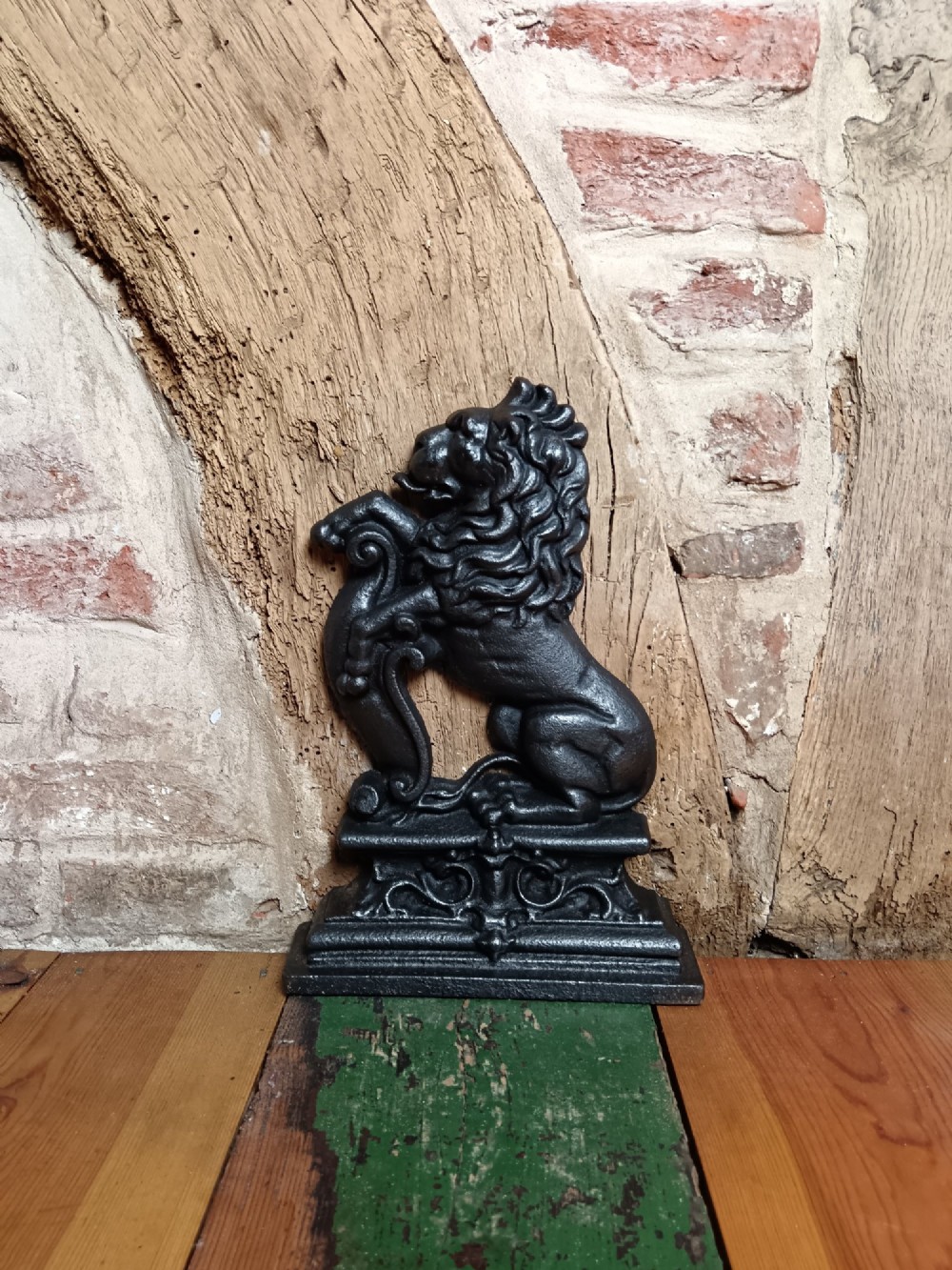A black cast iron doorstop depicting a heraldic lion rampant seated on a decorated scrollwork base. View VII