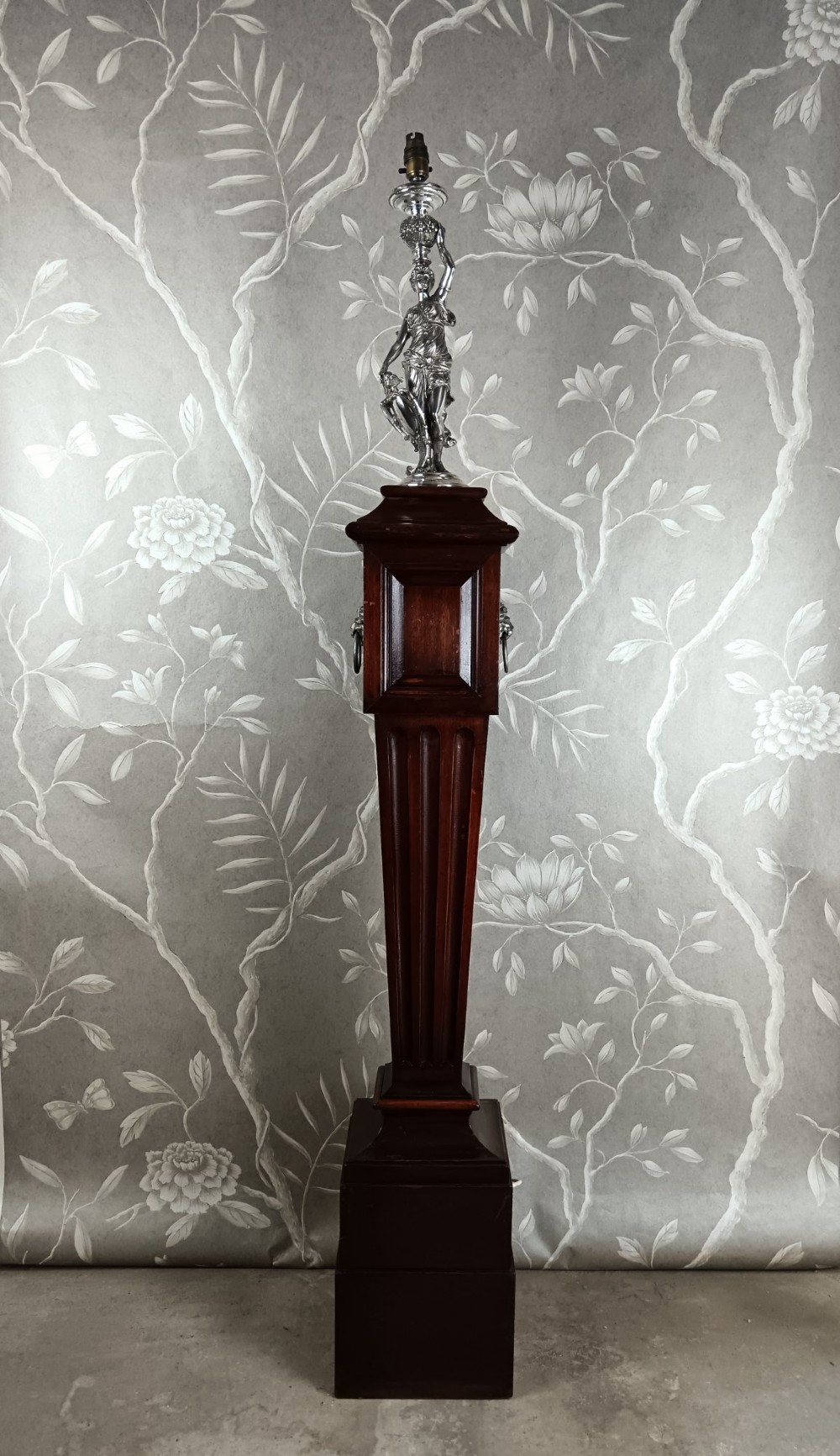 A dark wood tapered fluted pedestal column topped with a silver-plated classical female figural lamp fixture.