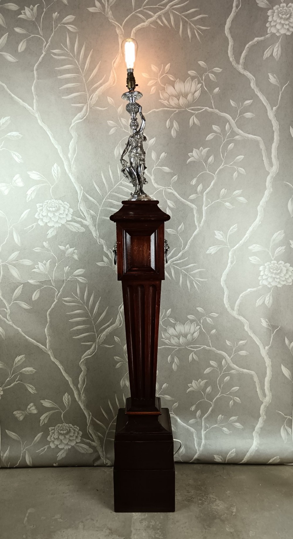 A dark wood tapered fluted pedestal column topped with a silver-plated classical female figural lamp fixture. View XV